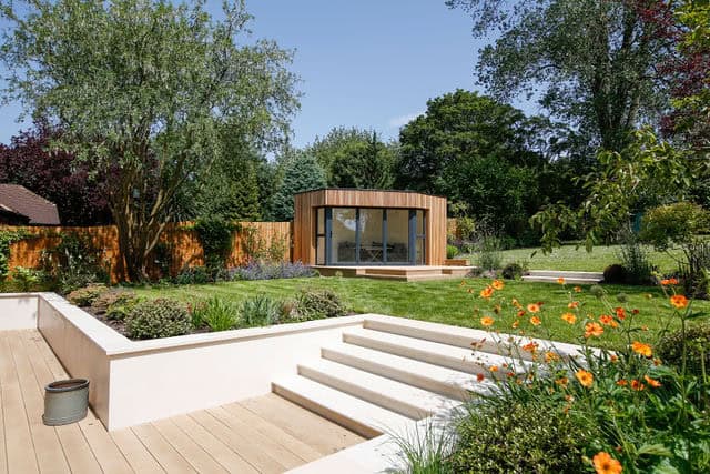 A wide flight of steps that leads from a sunny decked area into a large contemporary garden
